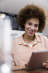 Smiling young woman using digital tablet in a cafe - WESTF021662