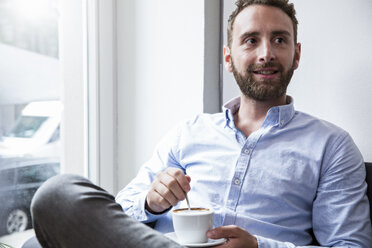 Young man with cup of coffee at the window - WESTF021667