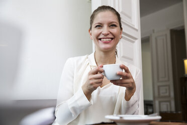 Lächelnde junge Frau mit einer Tasse Kaffee - WESTF021668