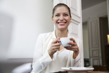 Smiling young woman with cup of coffee - WESTF021668