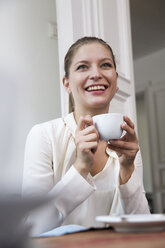 Smiling young woman with cup of coffee - WESTF021669