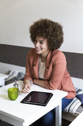Lächelnde junge Frau mit digitalem Tablet in einem Cafe - WESTF021673