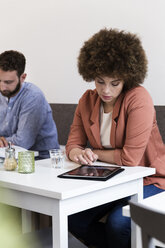 Junge Frau benutzt digitales Tablet in einem Café - WESTF021674