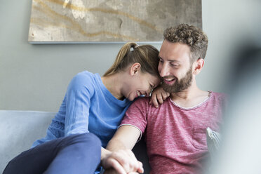 Glückliches junges Paar sitzt auf einer Couch - WESTF021700