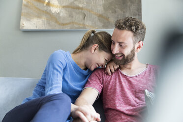 Happy young couple sitting on couch - WESTF021700