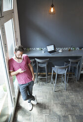 Junger Mann in einem Café mit Mobiltelefon - WESTF021706