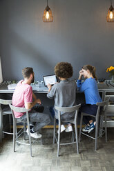 Three young people in a cafe using laptop - WESTF021707
