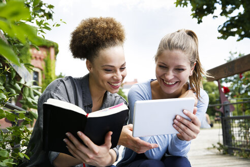 Two happy young women with diary and tablet outddors - WESTF021728