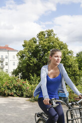 Young woman riding bicycle in park - WESTF021739