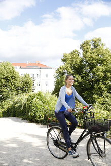 Junge Frau fährt Fahrrad im Park - WESTF021740