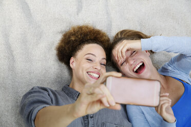 Zwei glückliche junge Frauen machen ein Selfie auf einer Decke - WESTF021746