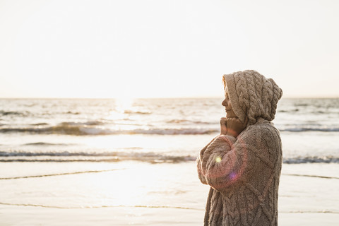 Frankreich, Halbinsel Crozon, Frau in Strickjacke am Strand bei Sonnenuntergang, lizenzfreies Stockfoto