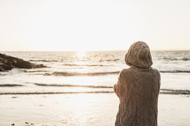 France, Crozon peninsula, woman wearing a cardigan on the beach at sunset - UUF008331