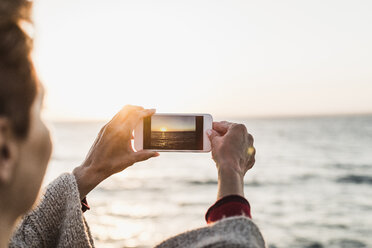 France, Crozon peninsula, woman taking a picture with smartphone - UUF008341