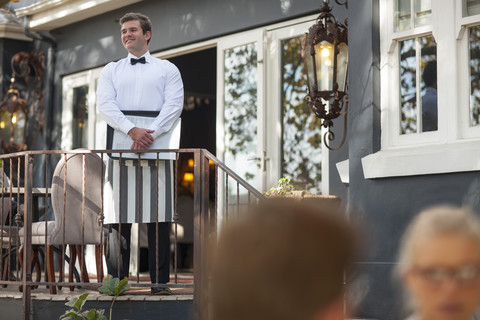 Kellner auf der Veranda, der sich im Außenrestaurant umsieht, lizenzfreies Stockfoto