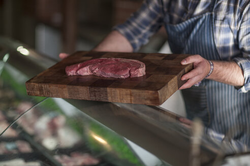 Metzger hält rohes Steak auf Holzbrett - ZEF010287