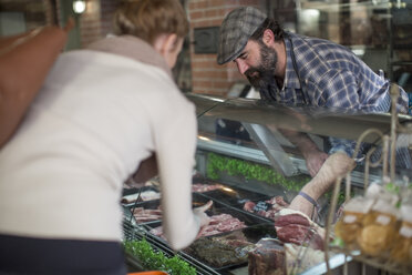 Client choosing meat from butchery display - ZEF010294