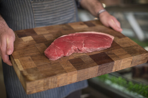 Metzger hält rohes Steak auf Holzbrett - ZEF010296