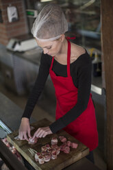 Woman working in a butchery rolling bacon meat rolls - ZEF010304