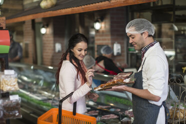 Butcher showing meat to woman in butchery - ZEF010308