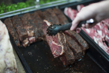 Hand taking meat from display in butchery - ZEF010313