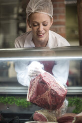 Woman putting meat on display in butchery - ZEF010314