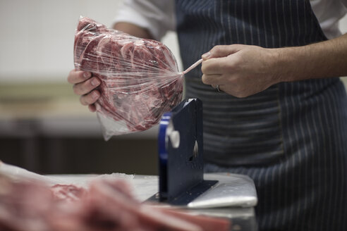 Metzger, der rohes Fleisch in der Metzgerei verpackt - ZEF010317