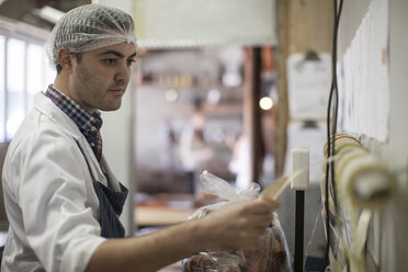 Butcher packing and labelling meat in butchery - ZEF010319
