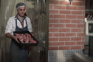 Butcher carrying tray with meat in butchery - ZEF010335