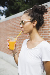 Young woman drinking an orange juice outdoors - MRAF000155