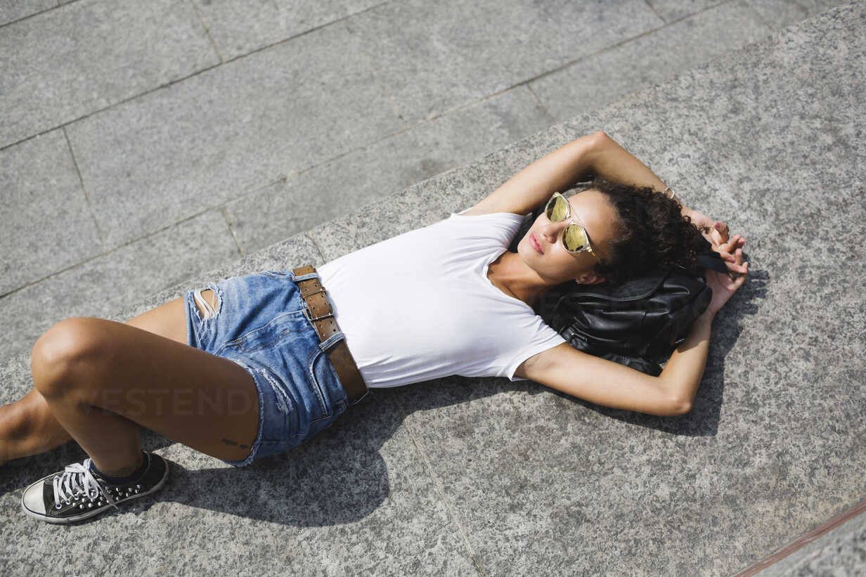 Relaxed young woman lying down enjoying the sunshine stock photo