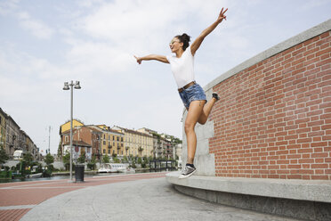 Exuberant young woman jumping outdoors - MRAF000169