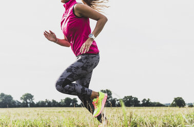 Young woman running in rural landscape - UUF008359