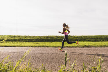 Young woman running on country road - UUF008364