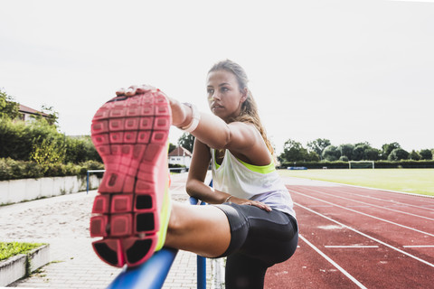 Junge Frau beim Dehnen in einem Leichtathletikstadion, lizenzfreies Stockfoto