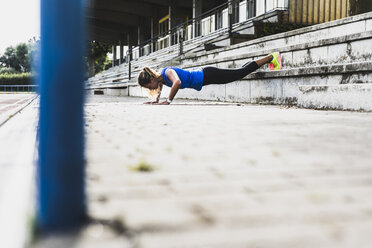 Young woman doing pushups on grandstand - UUF008387