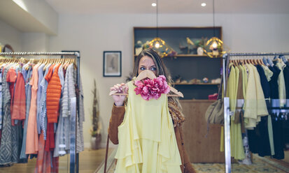 Frau hält Kleid in einer Boutique - DAPF000315