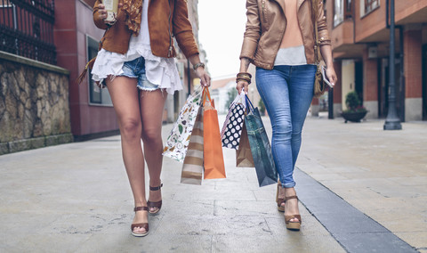 Low section of two women holding shopping bags walking in the city stock photo