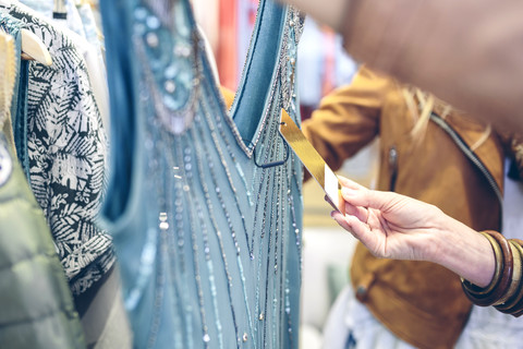 Nahaufnahme einer Frau, die das Preisschild eines Kleides in einer Boutique überprüft, lizenzfreies Stockfoto