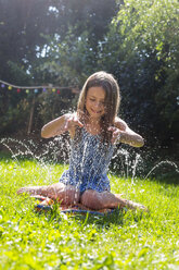Girl having fun with inflatable water cushion in the garden - SARF002860