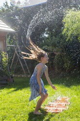 Girl having fun with inflatable water cushion in the garden - SARF002861