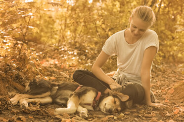 Junge Frau entspannt sich mit ihrem Hund in der Natur - FCF001069