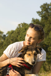 Porträt einer jungen Frau mit ihrem Hund im Sonnenlicht - FCF001071