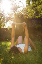 Mädchen liegt auf einer Wiese und macht ein Selfie mit Tablet - LVF005280