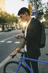 Teenager with a bike in the city, using smartphone - EBSF001725