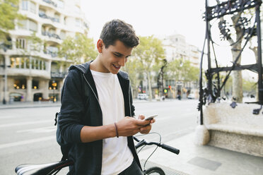 Teenager with a bike in the city, using smartphone - EBSF001729