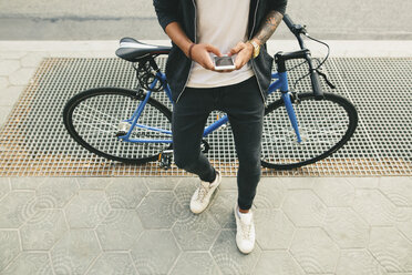 Jugendlicher mit einem Fahrrad in der Stadt, der sein Smartphone benutzt - EBSF001730