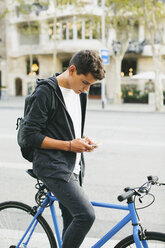 Teenager with a bike in the city, using smartphone - EBSF001732