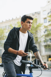 Teenager with a fixie bike in the city, smartphone - EBSF001733