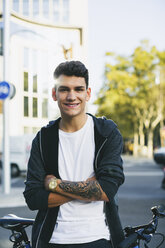 Smiling teenager with a bike in the city - EBSF001742